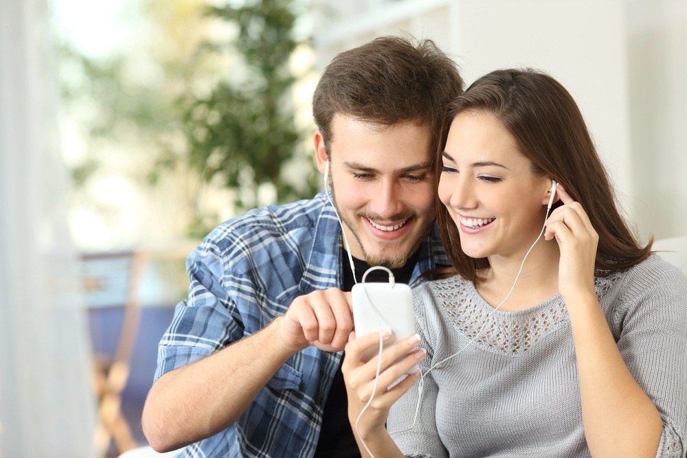 man and woman sharing thesame earpiece while listening to music