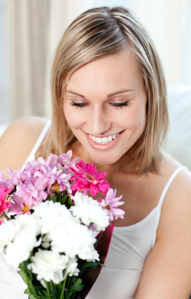 A lady blushing and gushing over the flowers her long-distant boyfriend sent her