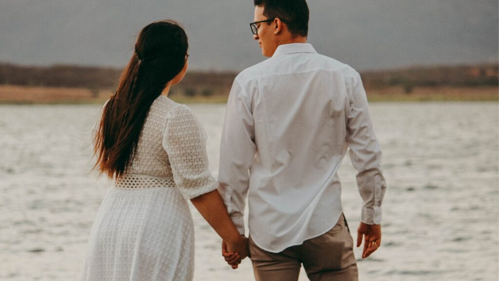 long distance couple taking a walk on the beach during summer holiday while asking questions about their beliefs and values