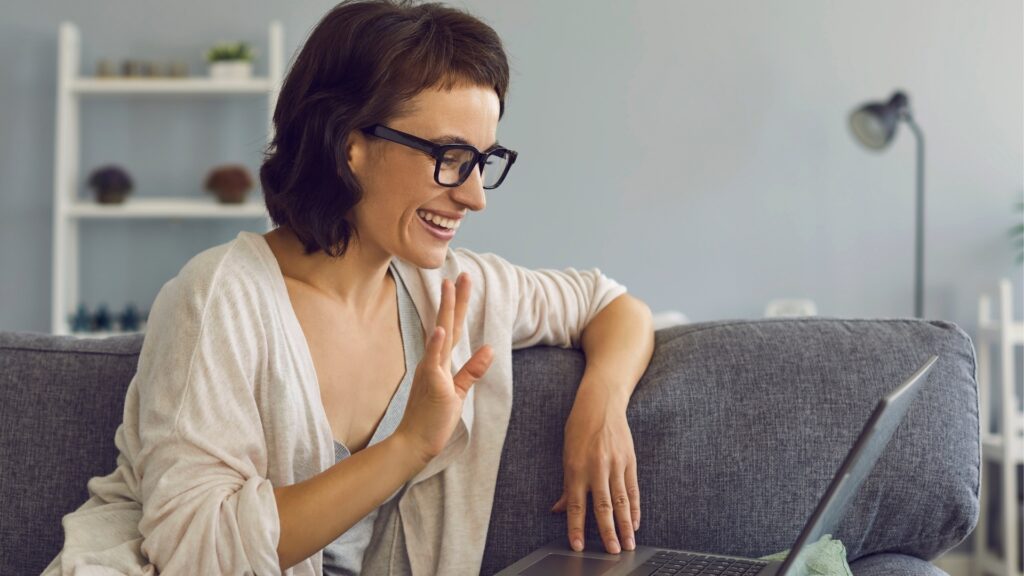 woman smiling at her partner during video call while she stylishly waits for him to introduce a topic for discussion