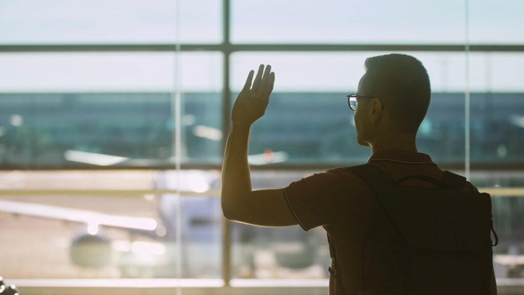 man waving into the thin air in hope to see the girlfriend at the airport