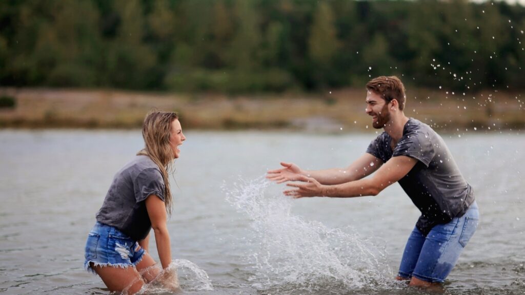 couple playfully splasing water on themselves during a road trip to a water fall