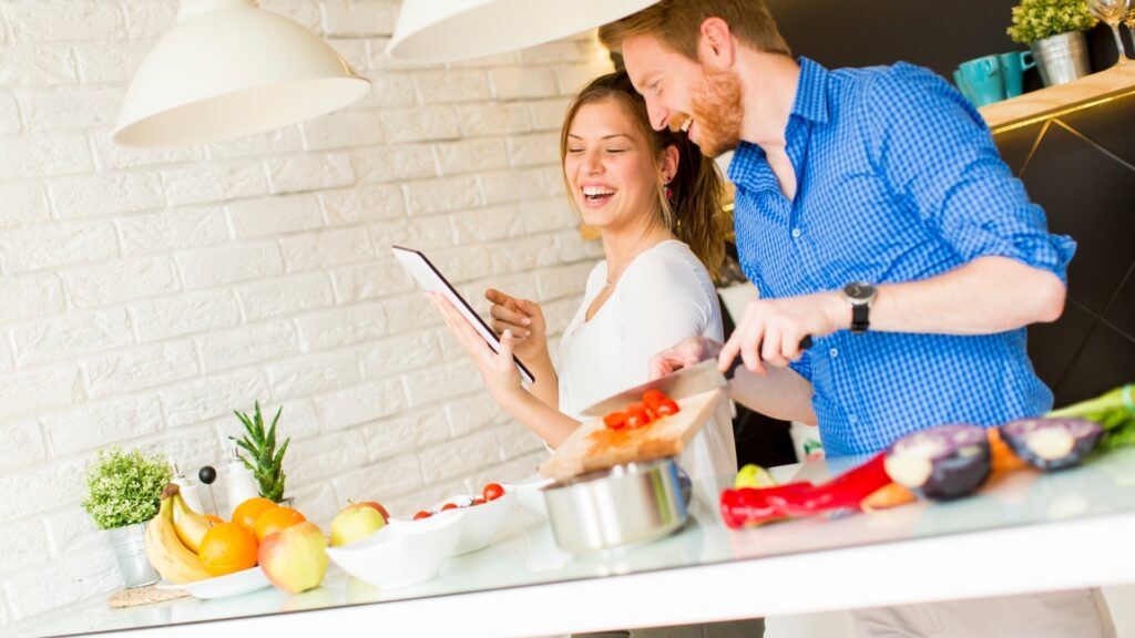 couple trying a new recipee in their kitchen while watching the steps virtually