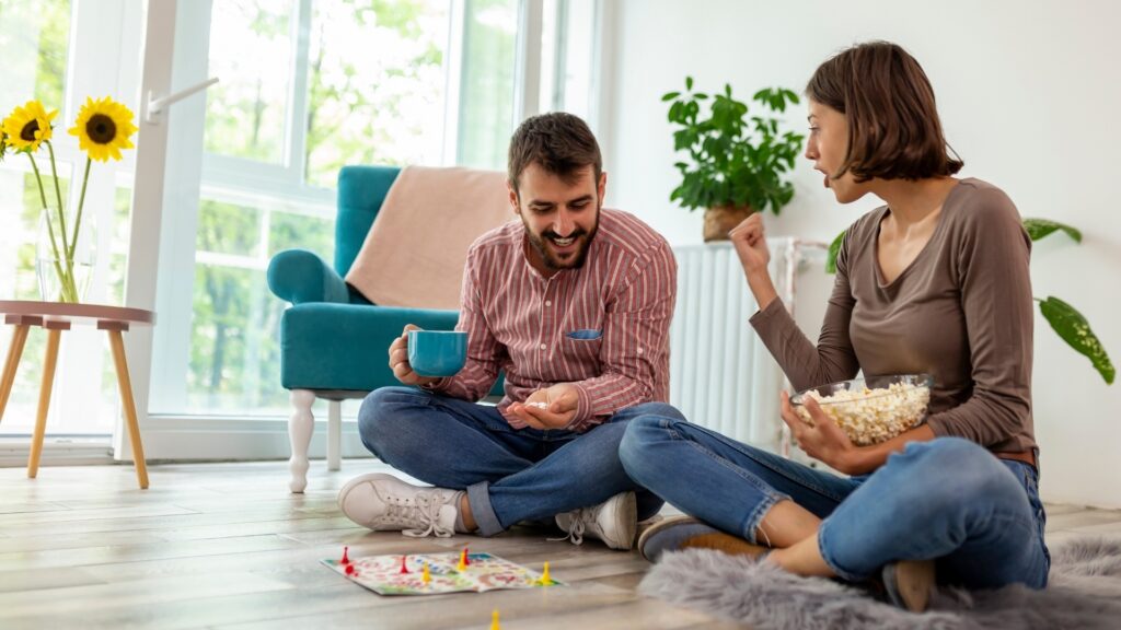 couple sitting on the floor with a bowl of popcorn each while interacting and playing a game 