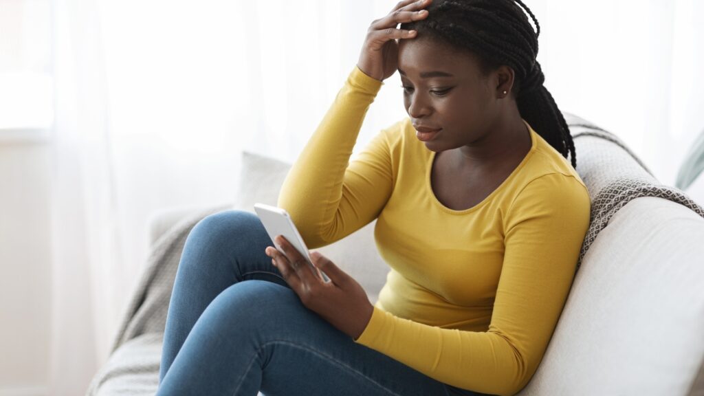 lady on yellow sitting on white sofa waiting for a reassuring text from long-distance partner