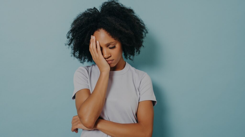 lady with afro hair feeling sad after she said she is fine and her long-distance partner took her word for it.