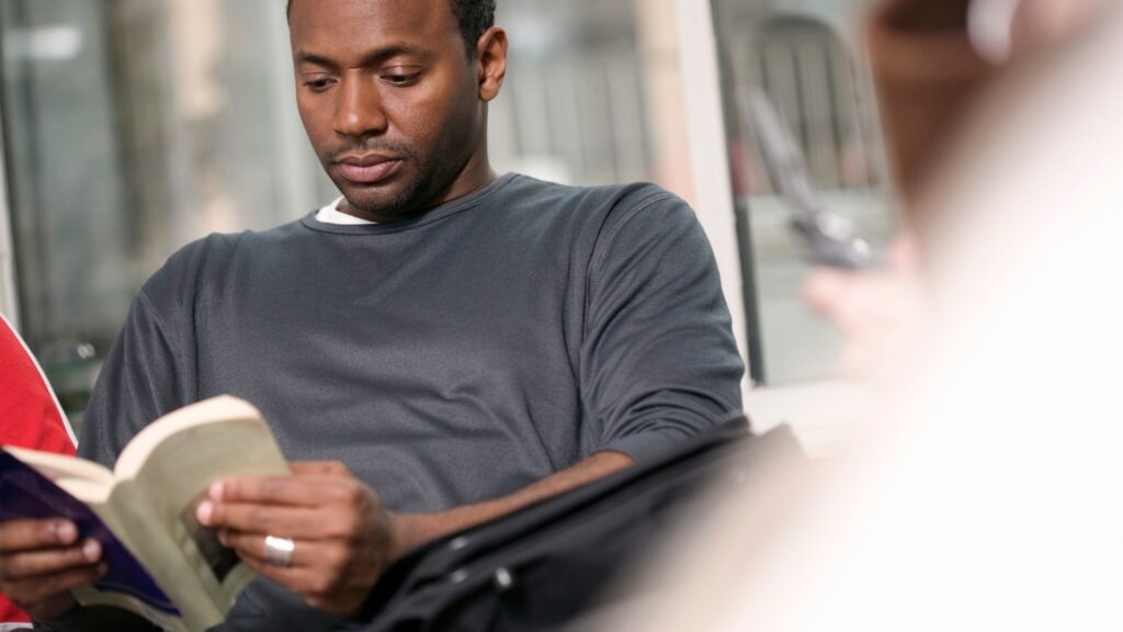 a black man paying close attention to the bbok he is reading