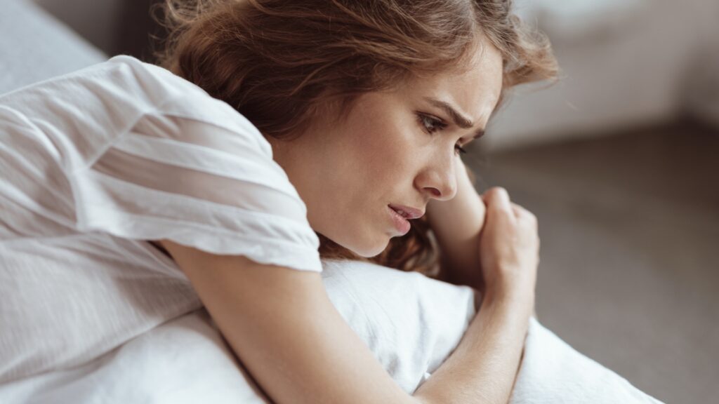 worried lady laying on bed 
