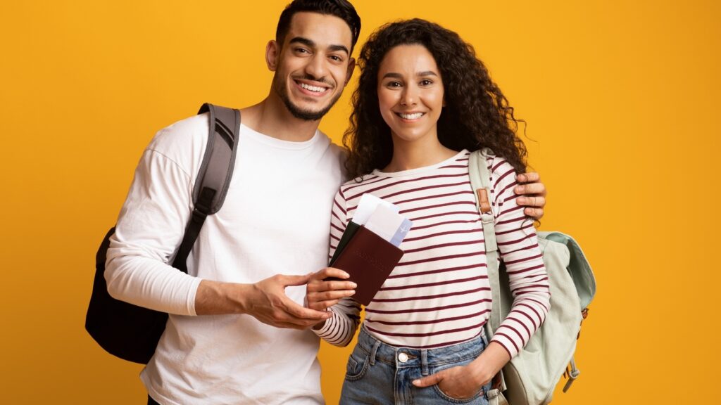 man and woman on yellow background holding plane tickets