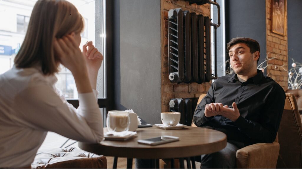 young long distance couple sitting across a table and having a conversation