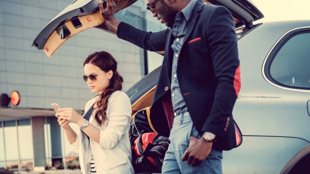 man opening his car boot for his lady to sit while they are on the road