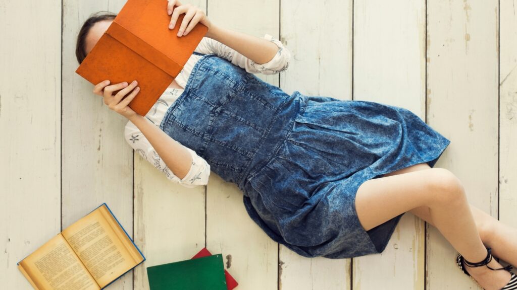 lady laying on a wooden floor reading her favorite journal from her long distance partner  