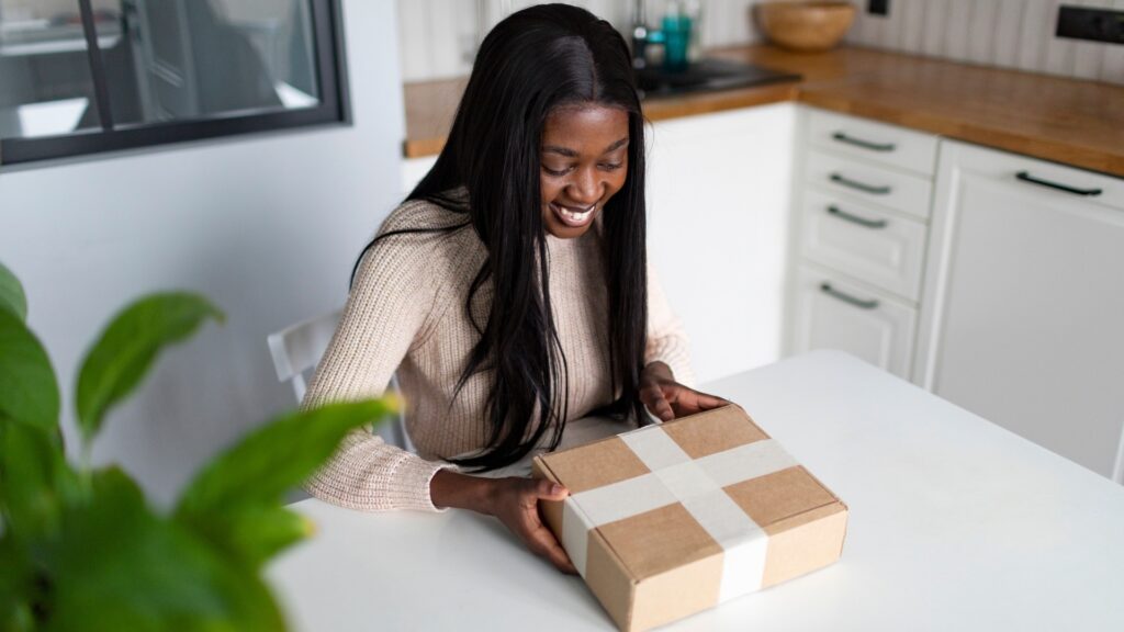 young african woman about to open her care package on her dinning table