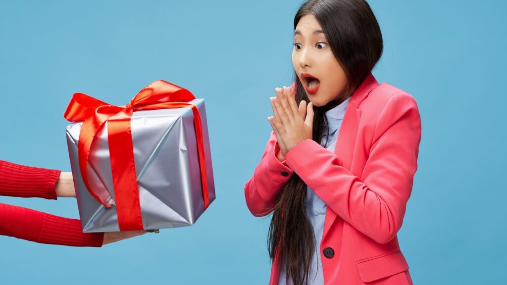 lady in a blue background surprised at the size of her surprise box 