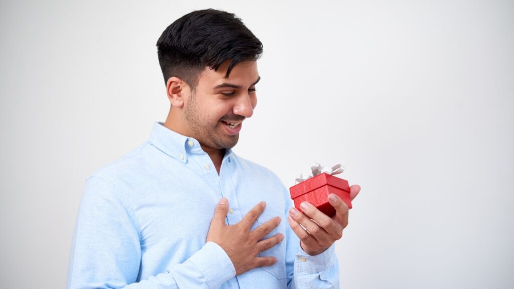 man on sky blue shirt admiring his gift box