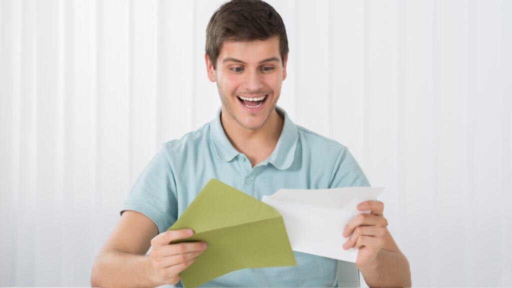 man smiling while reading a letter
