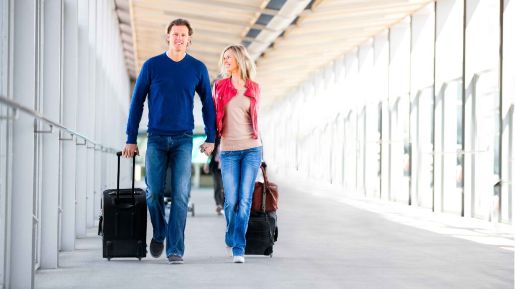couple walking down a hall way with their travelling bags